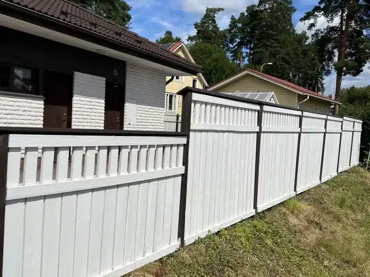 Valkoiseksi maalattu puuaita yrityksen ulkomaalauskohteessa